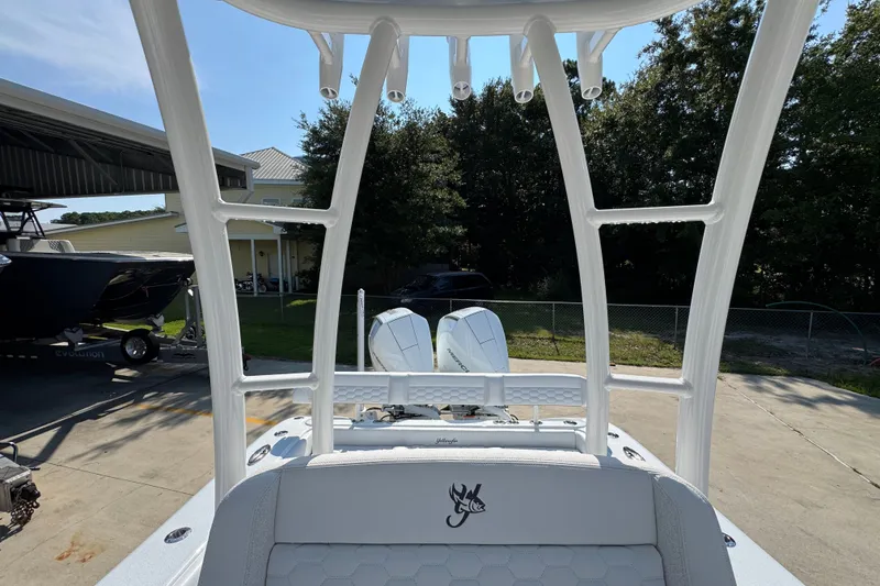 Slide: The Image of 2027 Yellowfin 26 Hybrid boat interior with rod holders and seating, parked outdoors. - 30