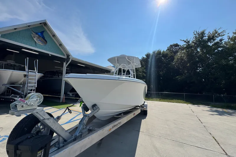 Slide: The Image of 2027 Yellowfin 26 Hybrid boat on trailer under sunny sky near a boatyard. - 5