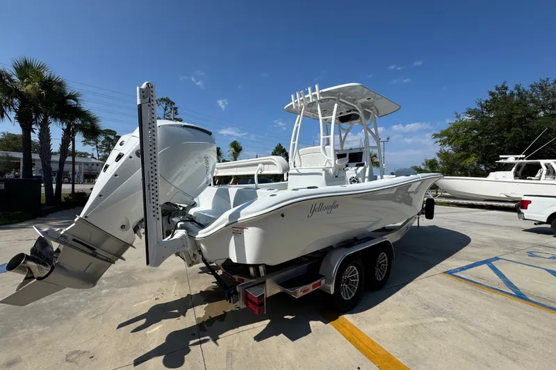 Slide: The Image of 2027 Yellowfin 26 Hybrid boat on trailer, parked outdoors under clear blue sky. - 12