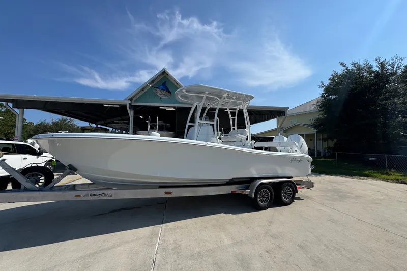 Slide: The Image of 2027 Yellowfin 26 Hybrid boat on trailer under clear blue sky. - 2
