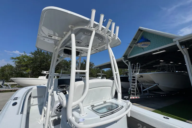 Slide: The Image of 2027 Yellowfin 26 Hybrid boat with T-top, docked near a boathouse under clear skies. - 37