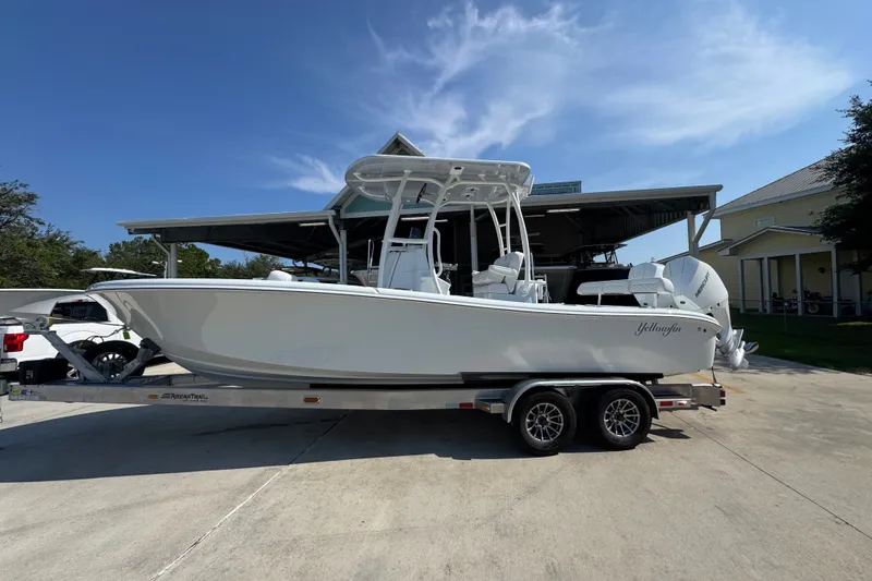 The Image of 2027 Yellowfin 26 Hybrid boat on trailer under clear blue sky. - 1