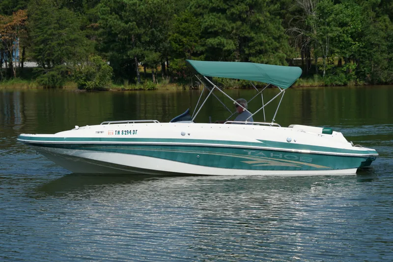Slide: The Image of 2007 Tahoe 215 I/O boat cruising on a serene lake with lush green surroundings. - 8