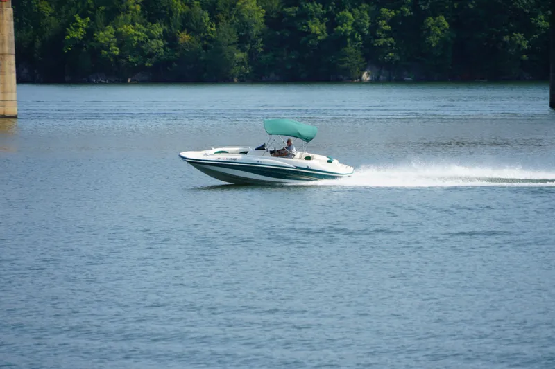 Slide: The Image of 2007 Tahoe 215 I/O boat speeding on a lake with lush green trees in the background. - 1