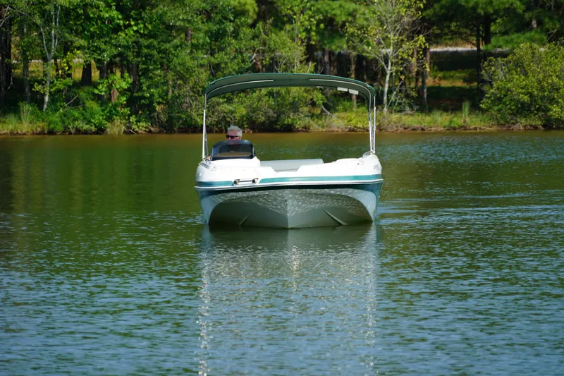Slide: The Image of 2007 Tahoe 215 I/O boat cruising on a serene lake with lush green surroundings. - 3