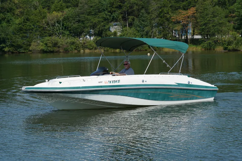The Image of 2007 Tahoe 215 I/O boat cruising on a serene lake with lush greenery. - 0