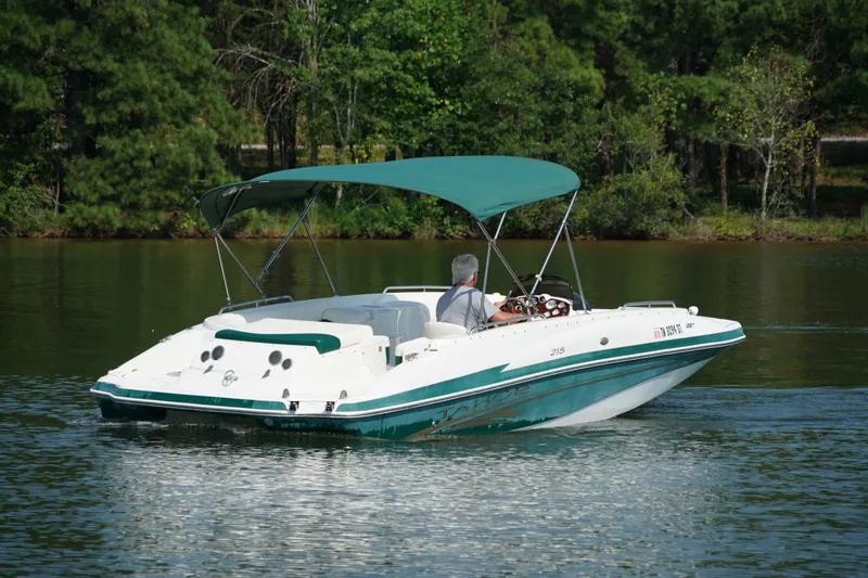 Slide: The Image of 2007 Tahoe 215 I/O boat cruising on a serene lake with lush green surroundings. - 6