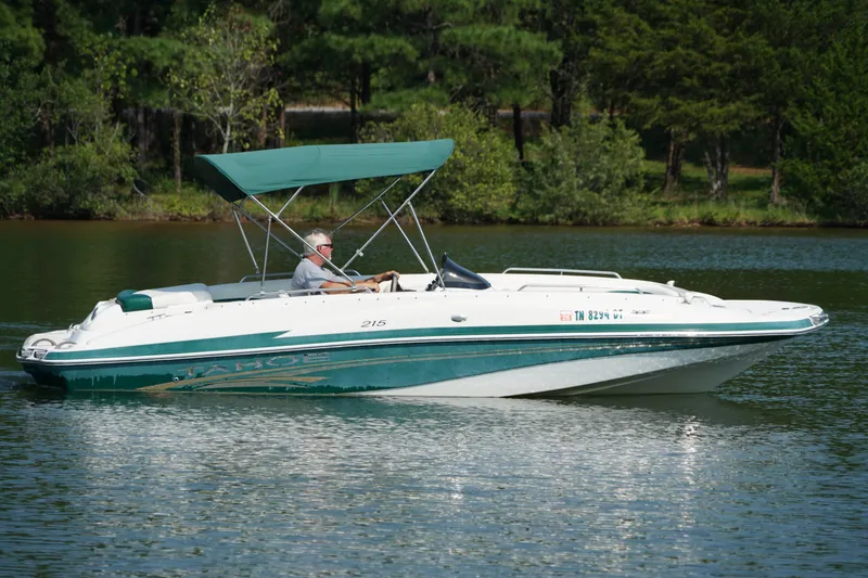 Slide: The Image of 2007 Tahoe 215 I/O boat cruising on a serene lake with lush greenery. - 5