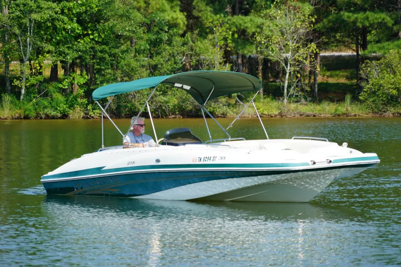 Slide: The Image of 2007 Tahoe 215 I/O boat cruising on a serene lake with lush green surroundings. - 4