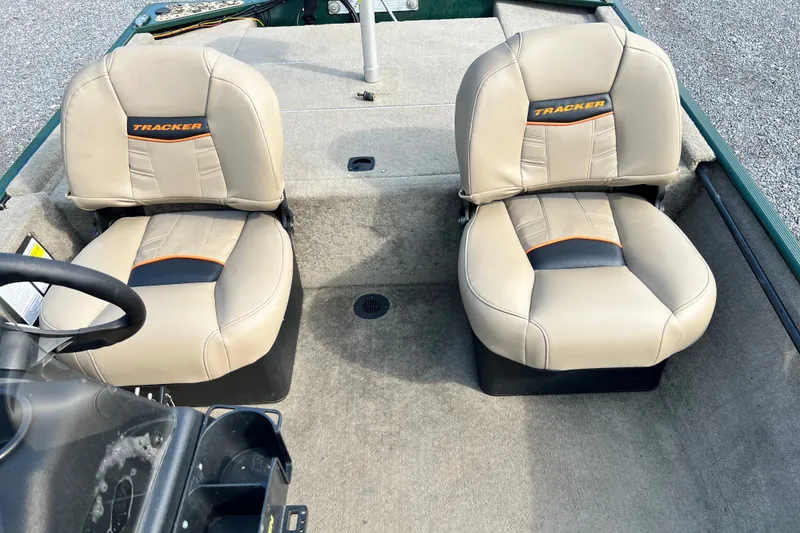 The Image of 2025 Bass Tracker III Classic boat seats, beige with orange accents, on a carpeted deck. - 1
