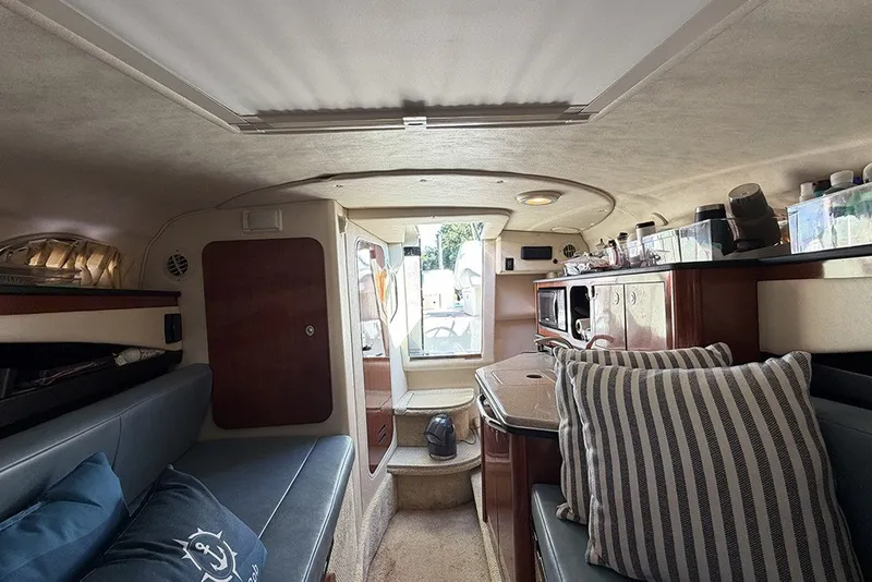 Slide: The Image of Interior of 2006 Sea Ray 270 Amberjack boat, featuring cozy seating and compact kitchen area. - 26
