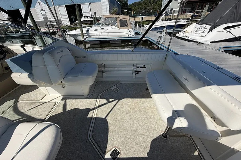 Slide: The Image of 2006 Sea Ray 270 Amberjack interior with white seating and docked boats in the background. - 5