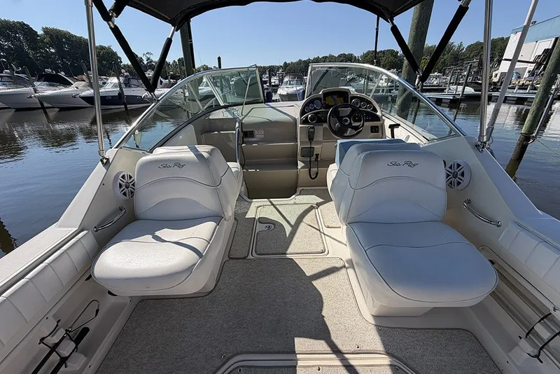 Slide: The Image of 2006 Sea Ray 270 Amberjack boat interior with white seating and steering console at marina. - 8