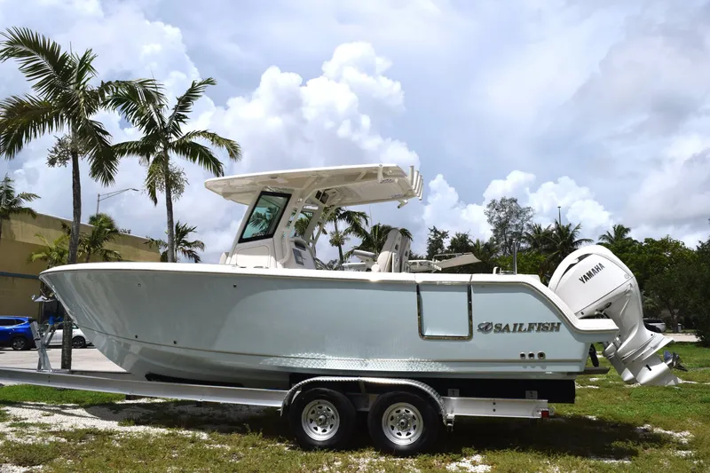 The Image of Sailfish 272 CC 2027: A modern motorboat on a trailer, surrounded by palm trees and cloudy skies. - 0