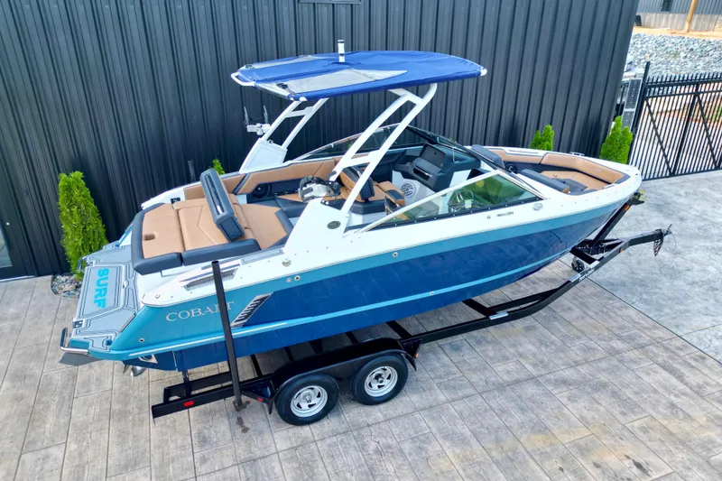 Slide: The Image of 2022 Cobalt R4 Surf boat on trailer, blue and white design, parked outdoors. - 8