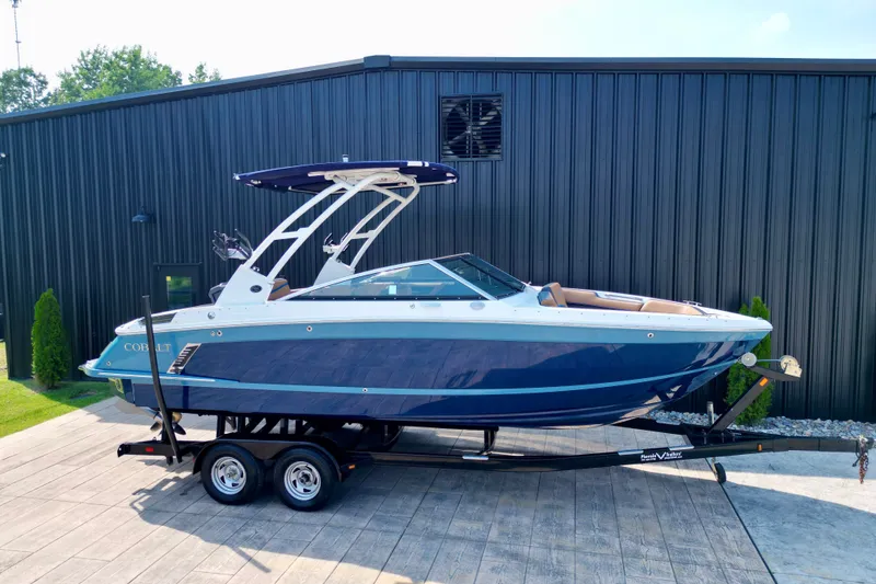Slide: The Image of 2022 Cobalt R4 Surf boat on trailer, parked beside a black building. - 6