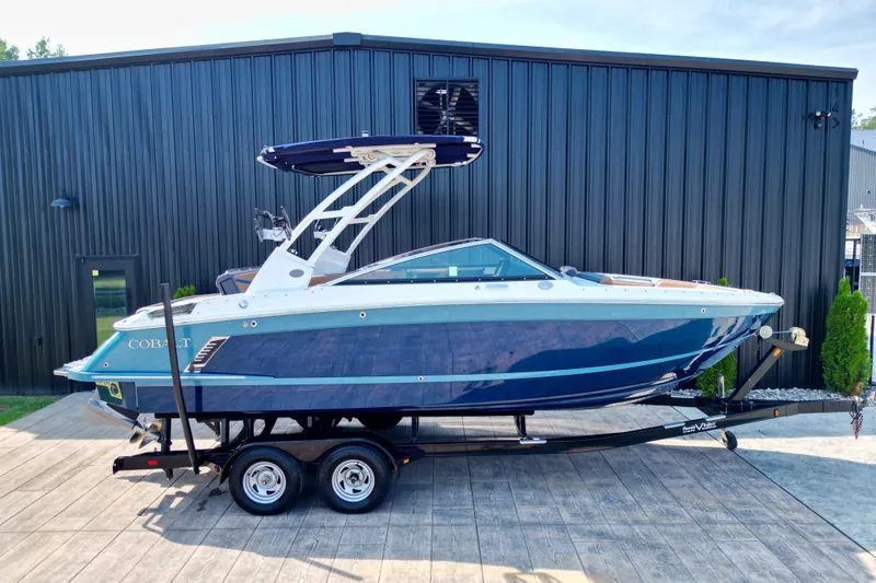 Slide: The Image of 2022 Cobalt R4 Surf boat on trailer, parked outside a black building. - 25