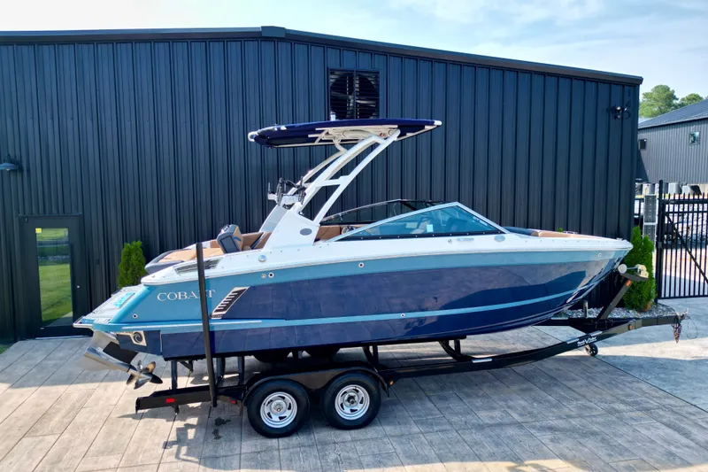 Slide: The Image of 2022 Cobalt R4 Surf boat on trailer, parked outside a modern building. - 21