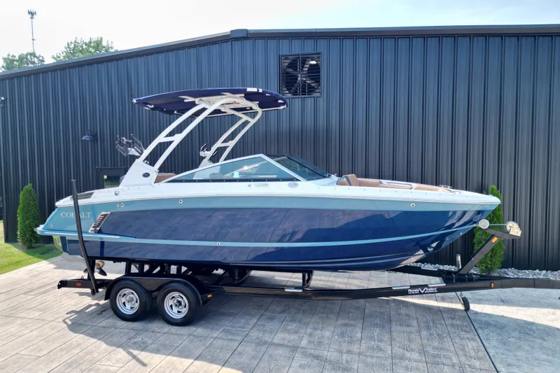 Slide: The Image of 2022 Cobalt R4 Surf boat on trailer, parked outside a black building. - 23
