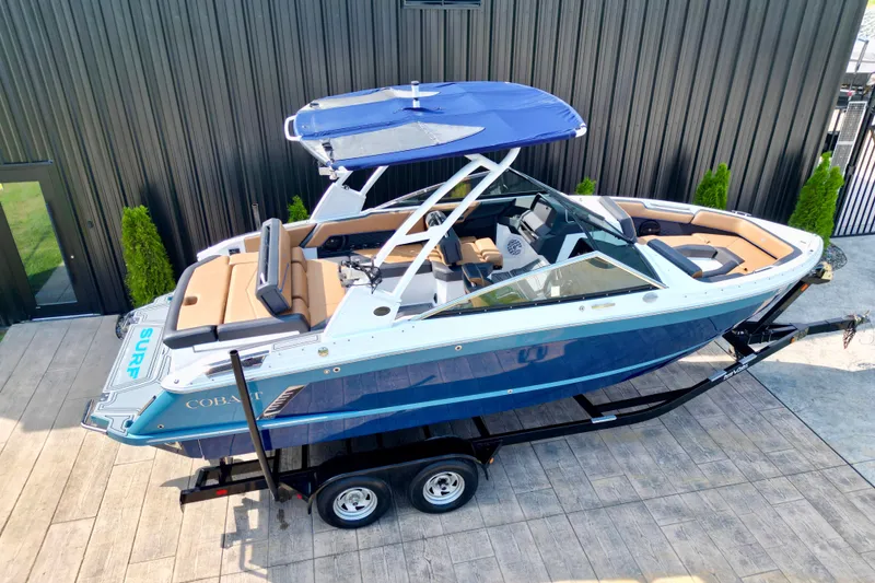 Slide: The Image of 2022 Cobalt R4 Surf boat on trailer, blue and white design, parked outdoors. - 4