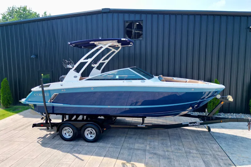 Slide: The Image of 2022 Cobalt R4 Surf boat on trailer, sleek design, blue and white exterior. - 1