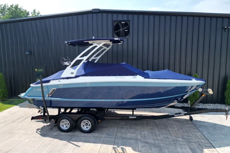 Slide: The Image of 2022 Cobalt R4 Surf boat on trailer, covered, parked outside a modern building. - 26