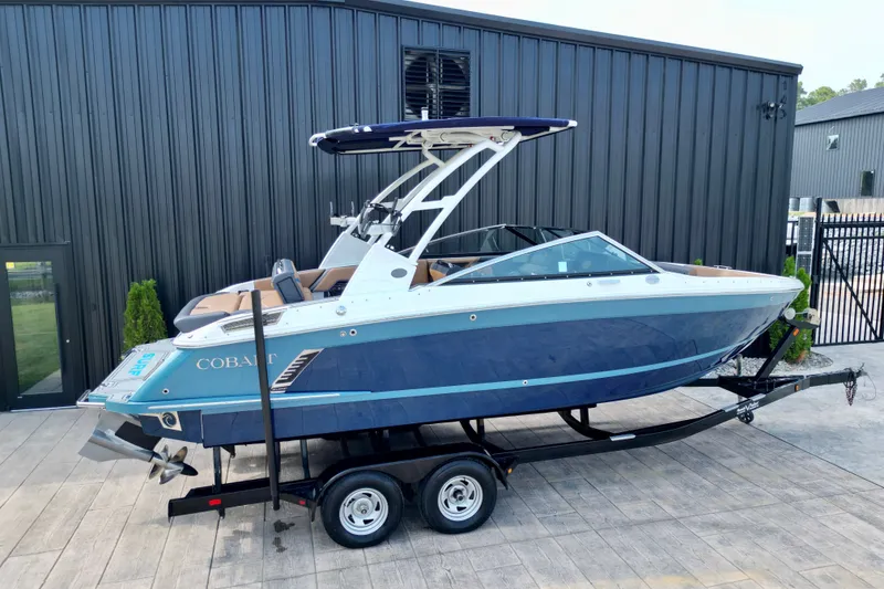 Slide: The Image of 2022 Cobalt R4 Surf boat on trailer, blue and white design, parked outdoors. - 5