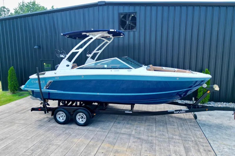 The Image of 2022 Cobalt R4 Surf boat on trailer, blue and white design, parked outdoors. - 0
