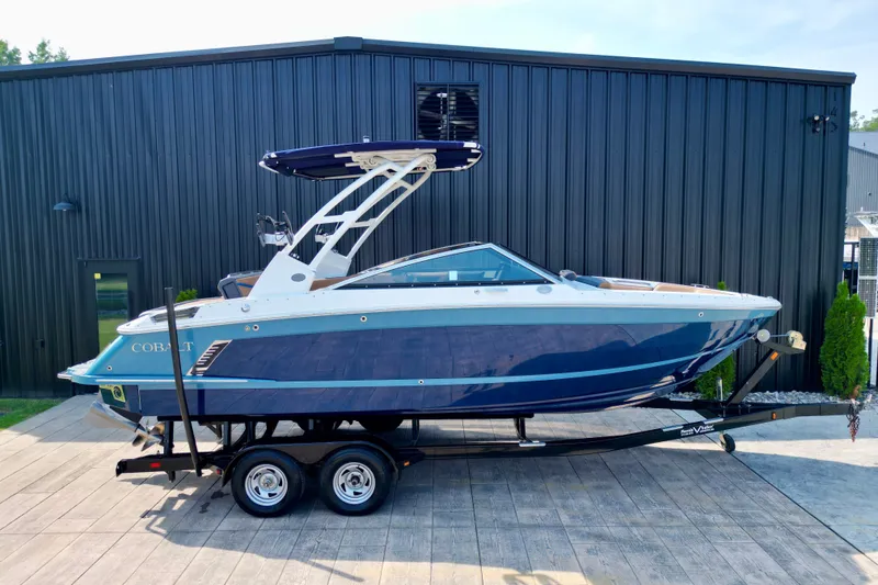 Slide: The Image of 2022 Cobalt R4 Surf boat on trailer, parked outside a black building. - 24