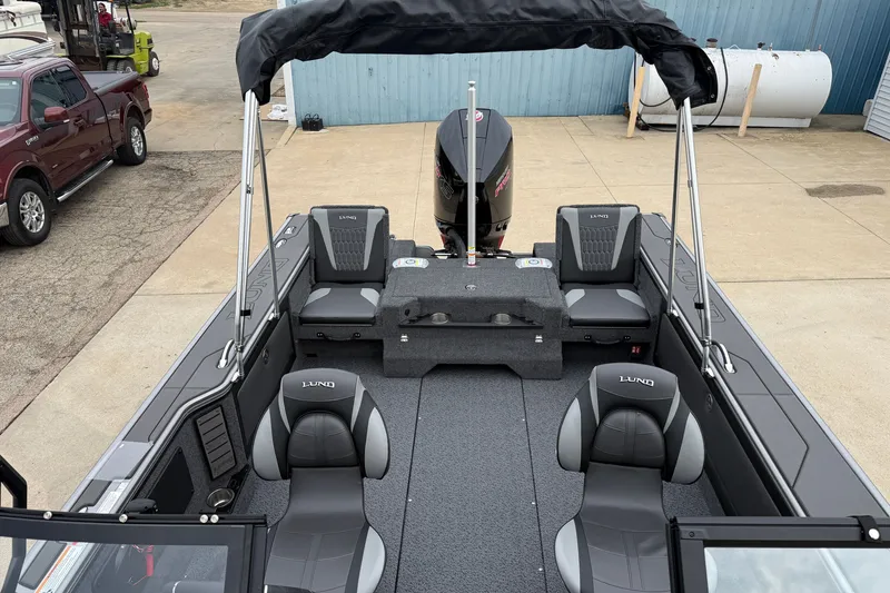 Slide: The Image of 2027 Lund 1975 Pro-V boat interior with seating and motor, parked on concrete. - 30