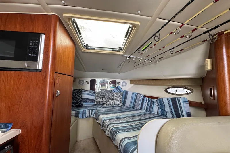 Slide: The Image of 1999 Tiara Yachts 2900 Open cabin interior with striped bedding and fishing rods. - 32