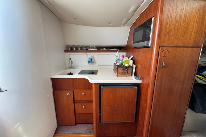 Slide: The Image of 1999 Tiara Yachts 2900 Open galley with wood cabinetry, sink, stove, and microwave. - 25