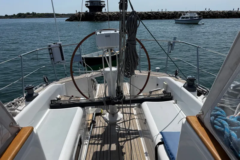 Slide: The Image of Cockpit view of 1988 Belliure 41 sailboat with steering wheel, docked in calm waters. - 69