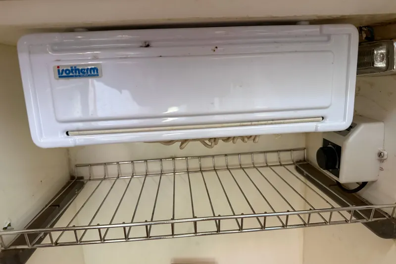 Slide: The Image of Isotherm refrigerator inside a 1988 Belliure 41 yacht, featuring a wire shelf and control knob. - 39