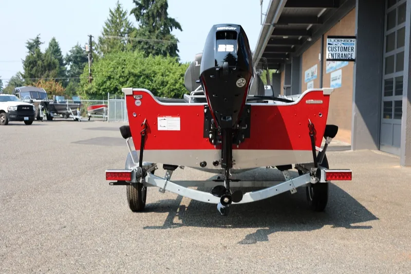 Slide: The Image of Red boat on a trailer, parked on asphalt, with an outboard motor and building in the background. - 23