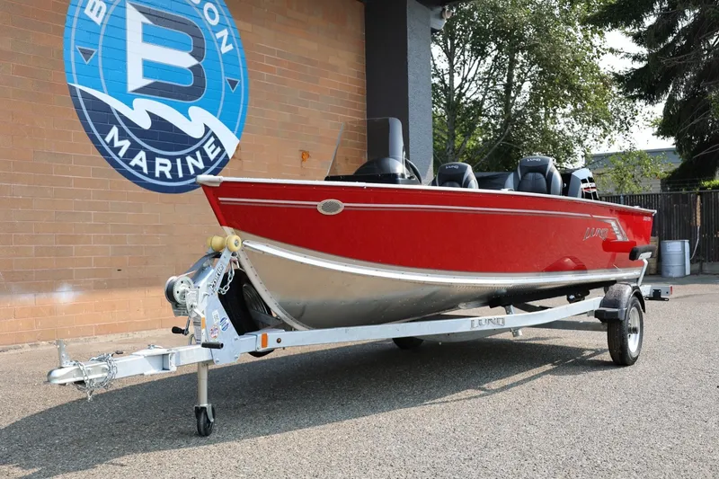 Slide: The Image of A red 2027 Lund 1600 Fury SS boat on a trailer in front of a brick wall. - 32