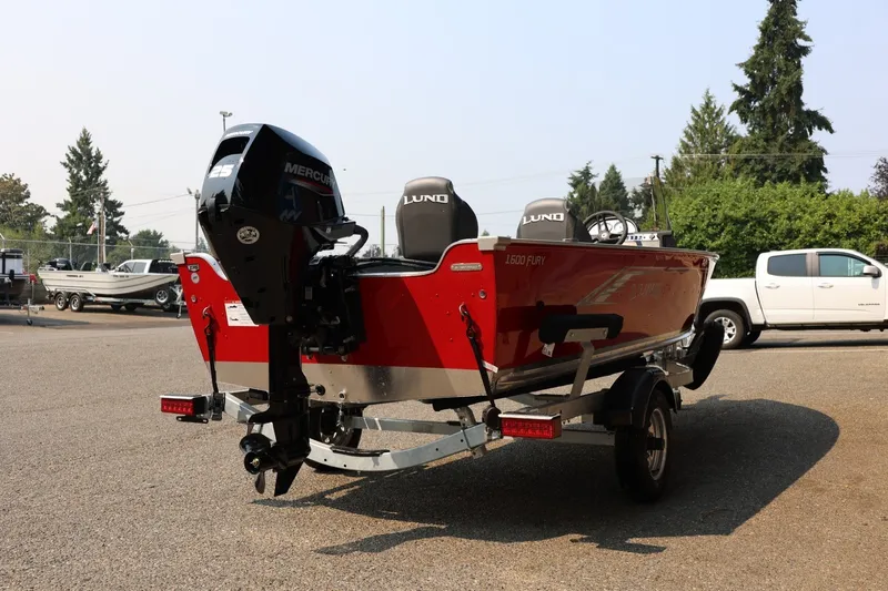 Slide: The Image of Red Lund 1600 Fury SS boat with Mercury engine on a trailer, parked on a gravel lot. - 26