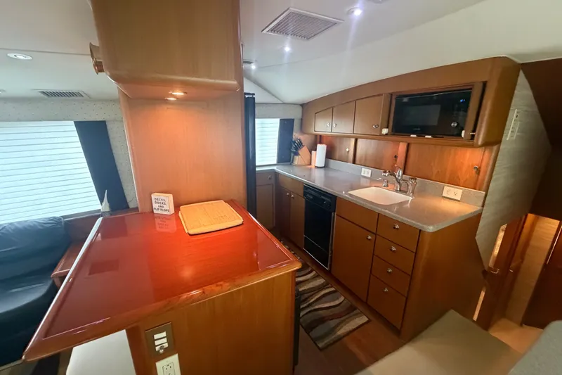 Slide: The Image of Luxurious kitchen interior of a 2001 Ocean Yachts 56 Super Sport, featuring wood cabinetry and modern appliances. - 24