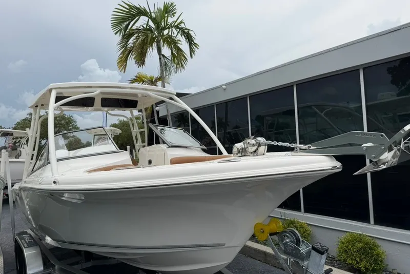 Slide: The Image of 2027 Key West 239 DFS boat on trailer, parked near modern building and palm tree. - 3