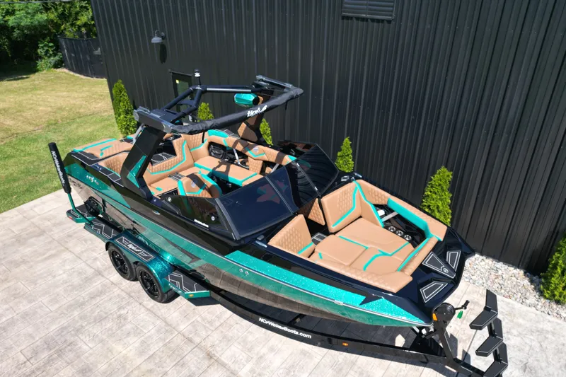 Slide: The Image of 2027 Tigé 22RZX boat with sleek design, vibrant teal and tan interior, parked outdoors. - 3