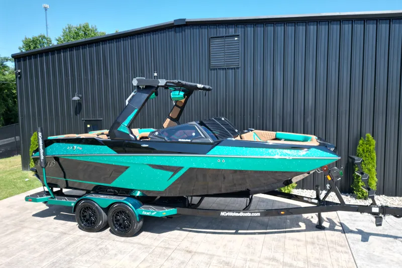 Slide: The Image of 2027 Tigé 22RZX boat in vibrant teal and black, parked on a trailer. - 18