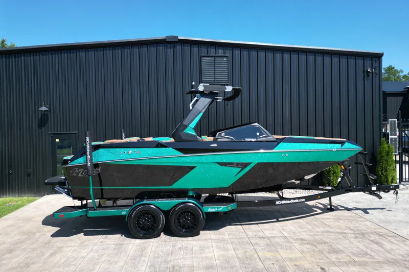 Slide: The Image of 2027 Tigé 22RZX boat in teal and black, parked on a trailer outside a black building. - 23