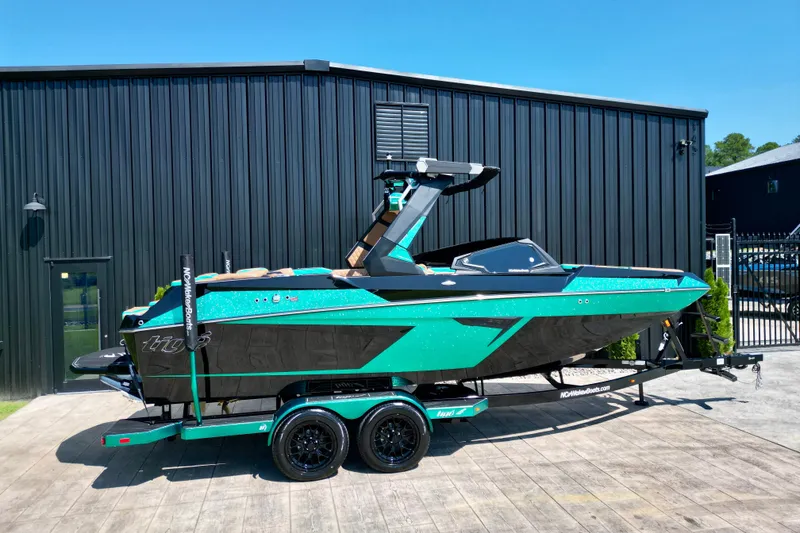 Slide: The Image of 2027 Tigé 22RZX boat in teal and black on a trailer, parked outside a building. - 21