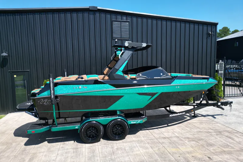 Slide: The Image of 2027 Tigé 22RZX boat in teal and black, parked on a trailer outside a building. - 20