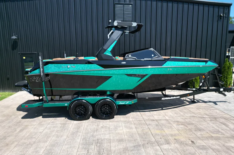 The Image of 2027 Tigé 22RZX boat in vibrant teal and black on a trailer, parked outdoors. - 0