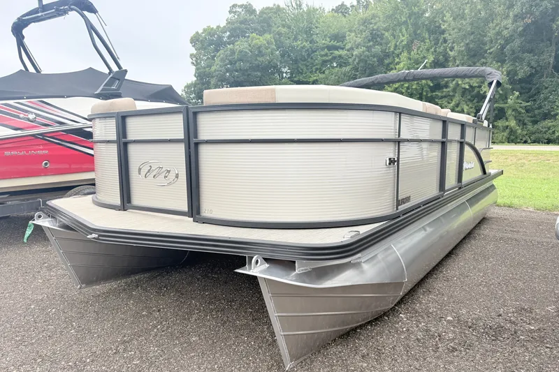 Slide: The Image of 2027 Manitou Aurora SE 21 pontoon boat parked on a gravel surface. - 2