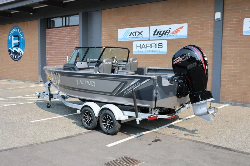 Slide: The Image of 2027 Lund 1875 Impact XS Sport boat on trailer, parked outside marine dealership. - 3