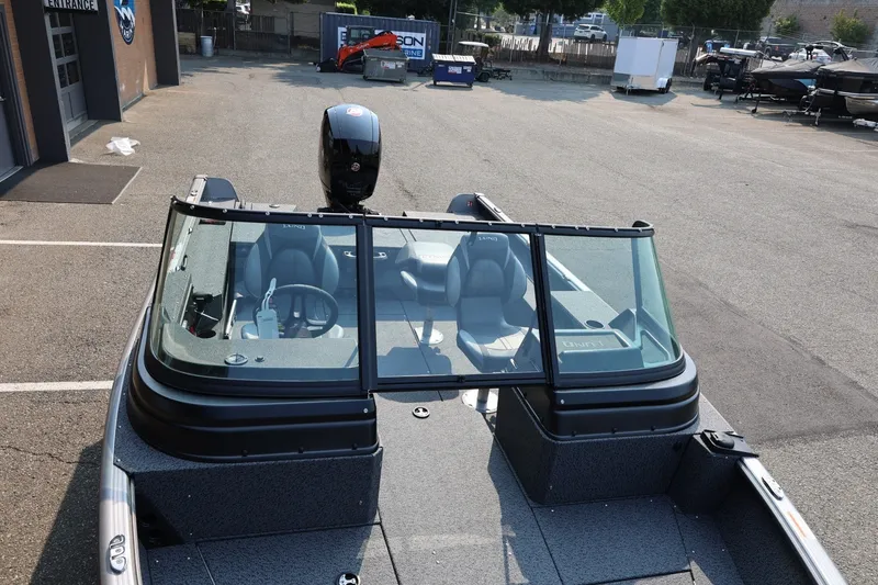 Slide: The Image of 2027 Lund 1875 Impact XS Sport boat with windshield and seating, parked outdoors. - 16