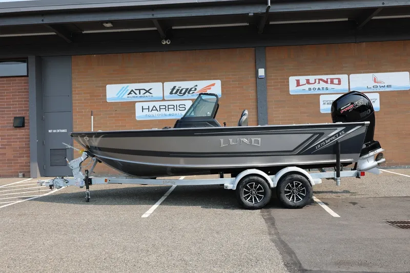 Slide: The Image of 2027 Lund 1875 Impact XS Sport boat on trailer, parked outside dealership. - 2