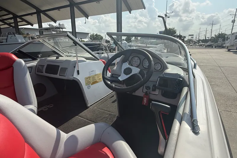 Slide: The Image of 2006 Skeeter SL 190 boat interior with steering wheel and red seats, parked outdoors. - 14